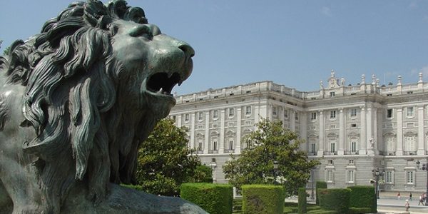 A statue of a lion in repose in front of the palace in Madrid