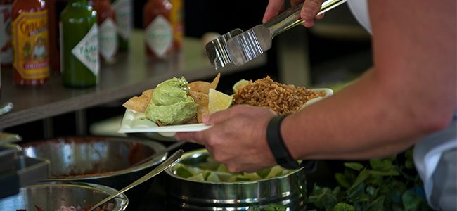 A diner assembles a plate of nachos