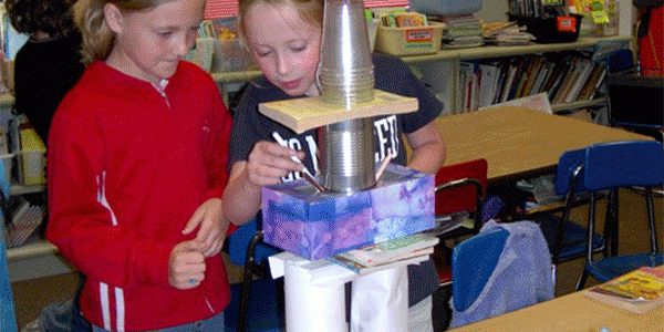 Two girls build a tower out of paper and plastic cups